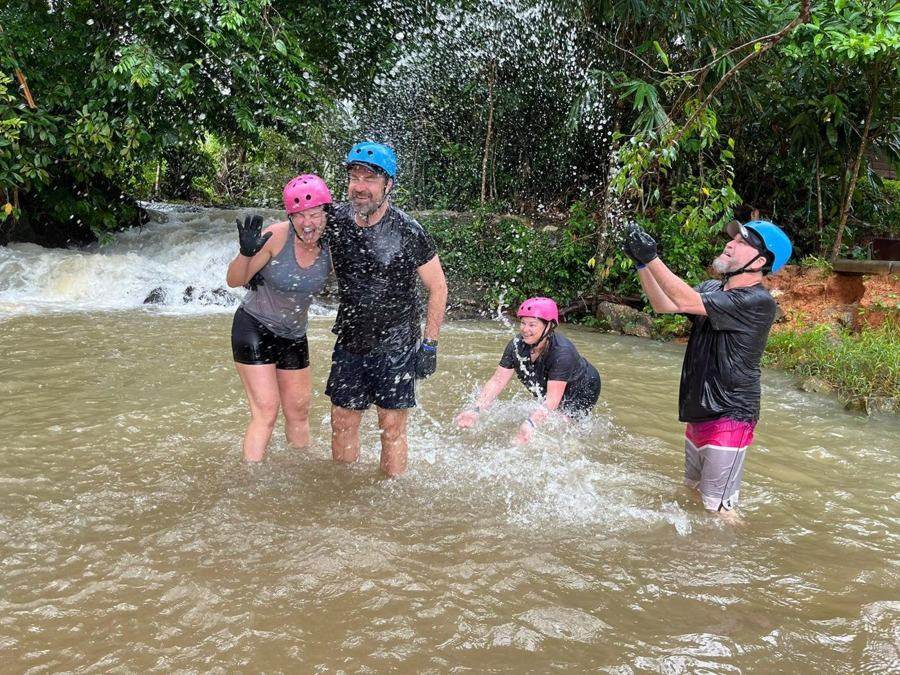 ATV riders splashing in a jungle river with Garden House ATV